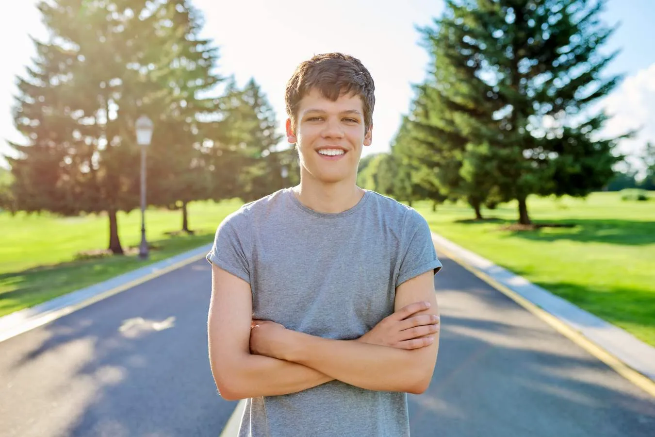 Teenage boy standing in the middle of a road and smiling