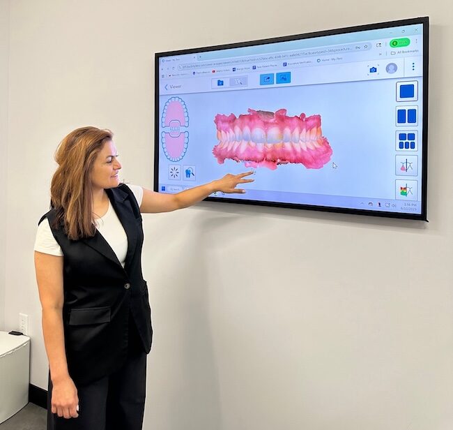 Dr. Bennie Yavari reviewing a 3D digital treatment plan on a wall display.