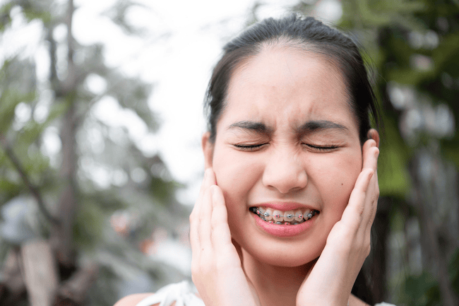 Young woman with braces feeling soreness 1